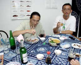 [写真]EYECOM店内にて刺身をつまみながら飲んでいる常連さんと長谷川氏