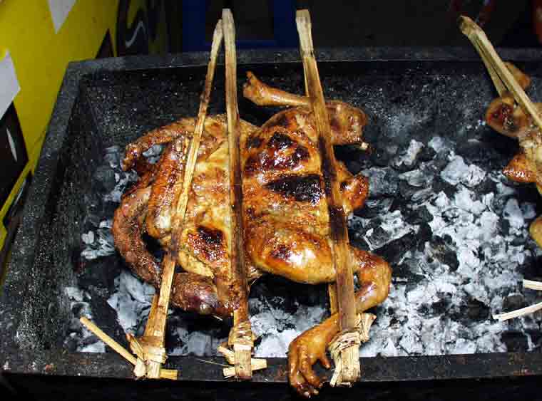 [料理の写真] 鶏を丸ごと竹串に挟んで炭火で焼いている