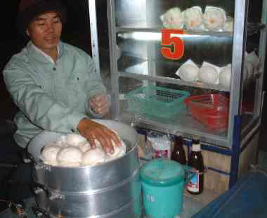 [写真] 一般的な屋台の中華饅頭屋。リアカーの屋台をバイクで引いている。