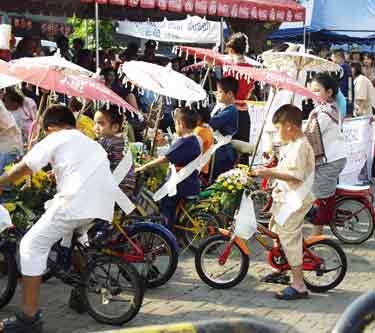 [写真]日傘を差しながら自転車に乗った子供達