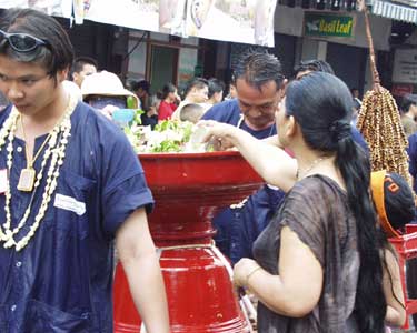 [写真] 供え物に溜まった水を汲み出す女性