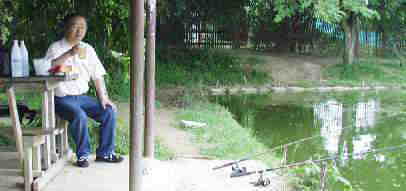 ナマズの釣堀でメコン（タイ国産のウィスキー）の水割りを飲んでいる私。
