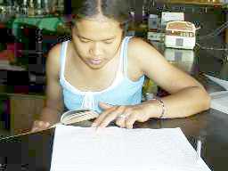 [写真]カウンターの中で、辞書を片手に勉強しているバイトの女性